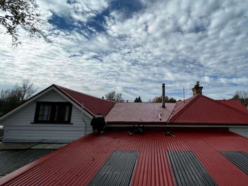 Grey longrun commercial roof photographed from the parapet with a cloudy sky above