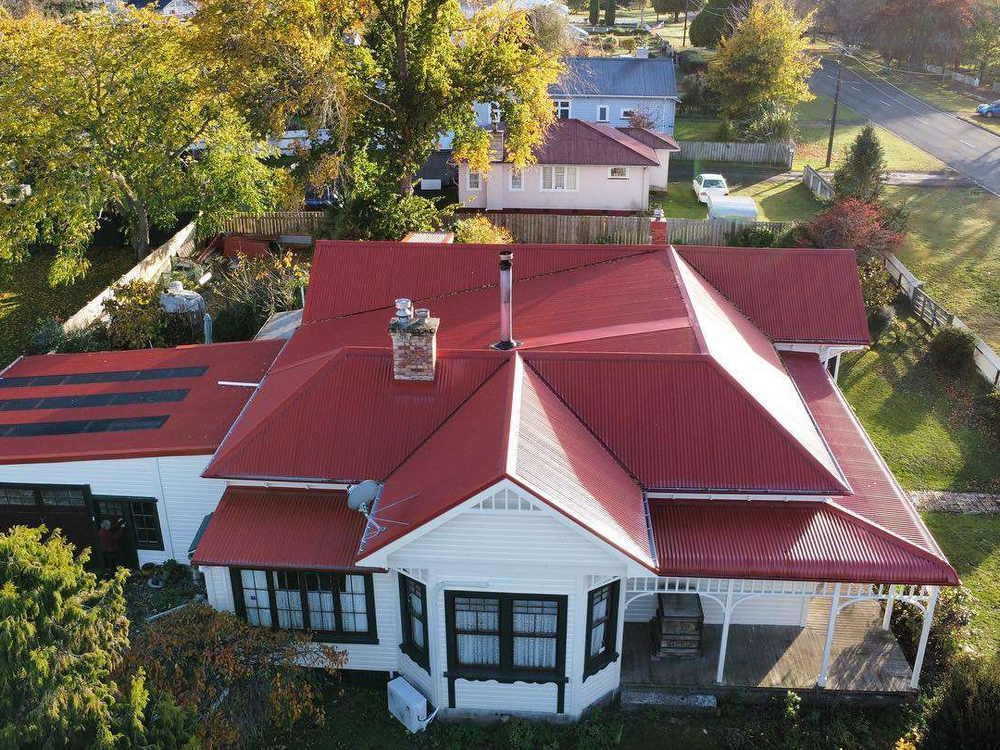 Aerial view of a villa with a bright red roof, bay window and solar panels