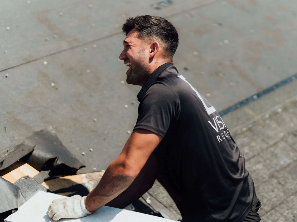 Roofer in a branded T shirt sitting on the roof deck, looking off to the side