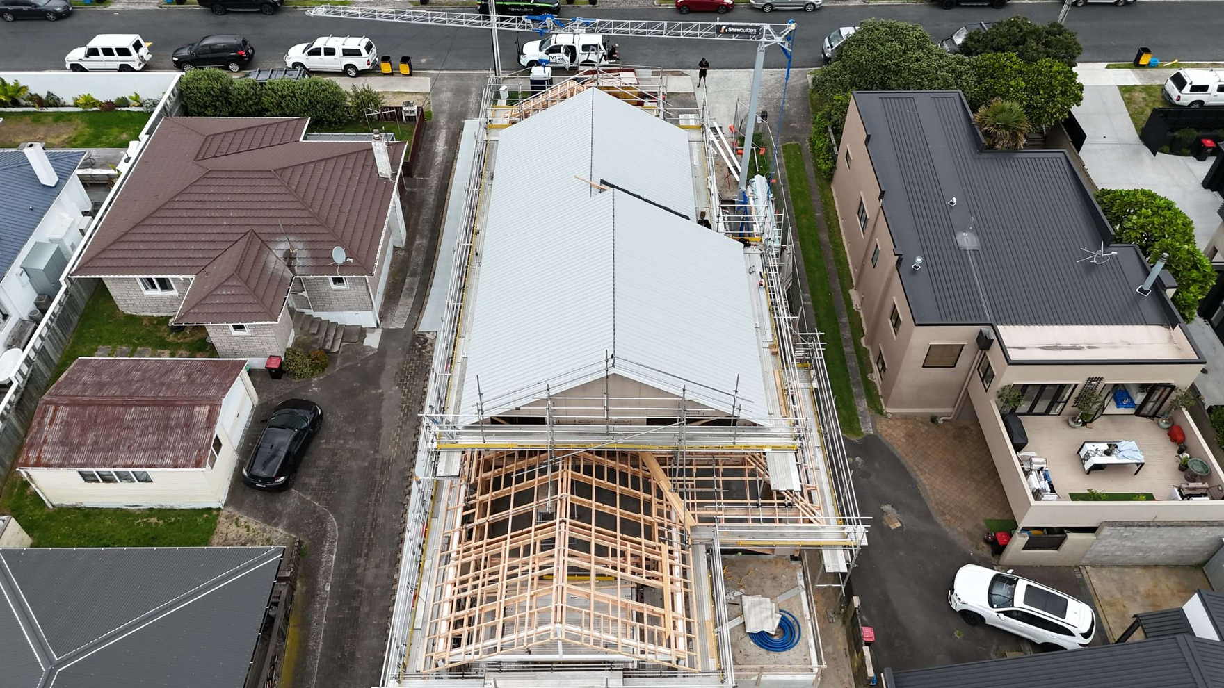 Aerial view of a new Tauranga house with roof trusses up and scaffolding around it, ready for roofing