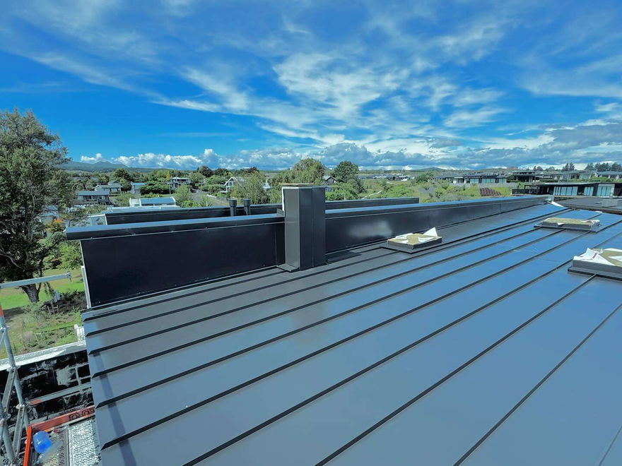 Architectural tray roofing with its raised standing seams running up to the ridge against a blue sky