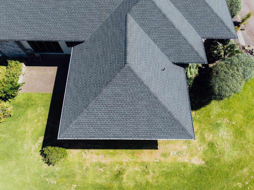 Overhead view of a grey asphalt shingle hip roof with clean ridge lines