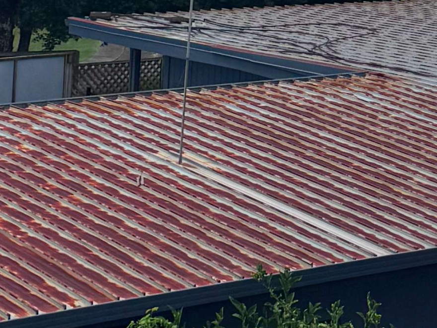 Faded and streaked red roof on a house, weathered and well past its best