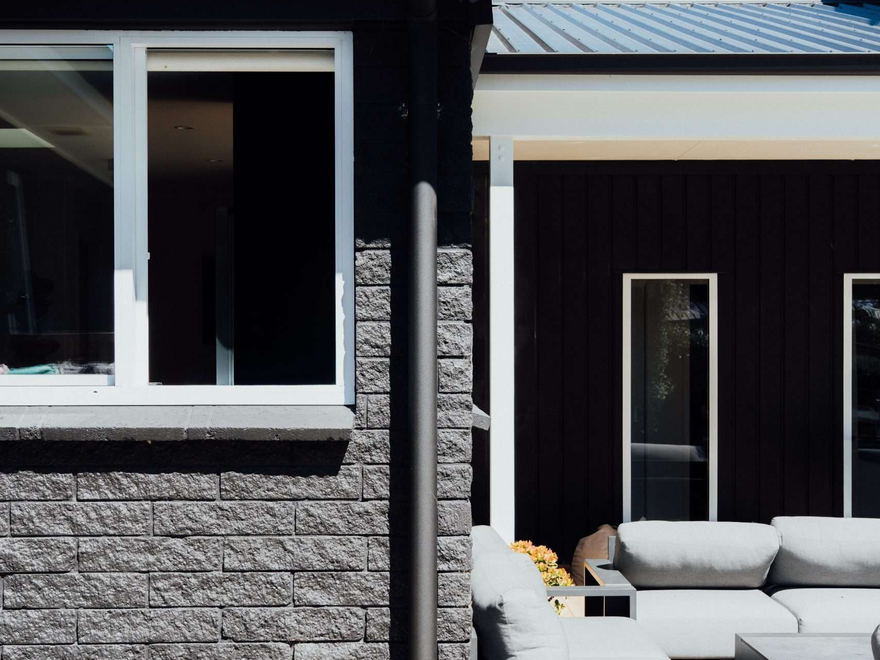 Downpipe running down the side of a black clad Tauranga house from a concealed gutter